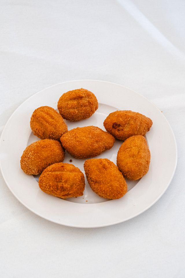 Bolitas de flamenquín recién fritas en un plato blanco