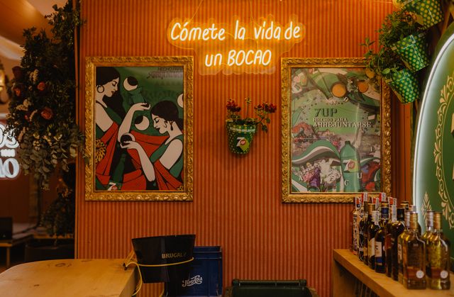 Neón «Cómete la vida de un bocao» entre dos cuadros ilustrados